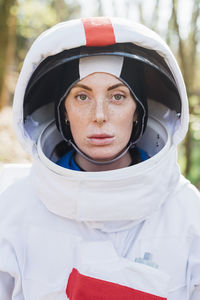 Female astronaut wearing space helmet and suit in forest