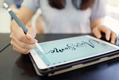 Midsection of woman using smart phone on table