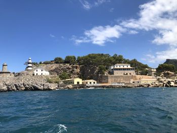 Buildings by sea against blue sky