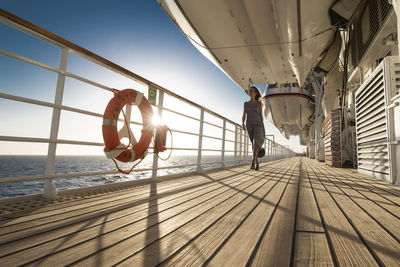 Rear view of people on railing by sea against sky