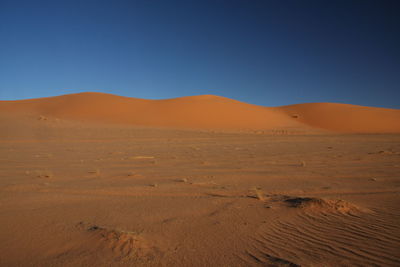 Scenic view of desert against clear blue sky