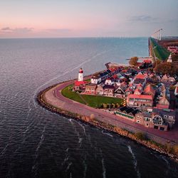 Scenic view of sea by buildings against sky during sunset, urk netherlands lighthouse 