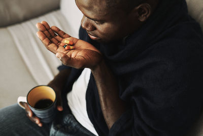 Midsection of man holding drink sitting at home