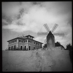 Low angle view of traditional windmill against cloudy sky