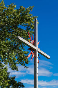 Low angle view of cross on tree against blue sky