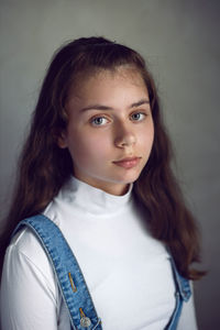 Portrait of a teenage girl in a white blouse on a gray background in the studio