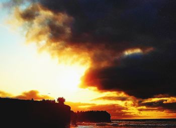 Scenic view of sea against dramatic sky during sunset