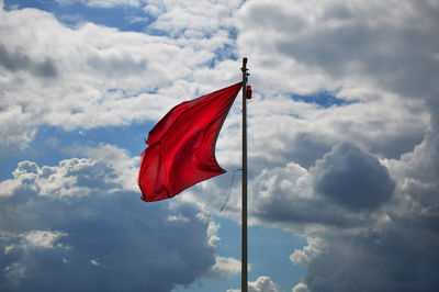 Low angle view of red flag against sky