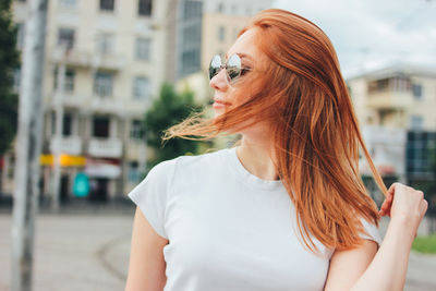 Beautiful woman with tousled hair wearing sunglasses in city