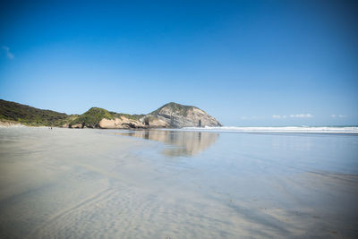 Scenic view of beach against clear blue sky