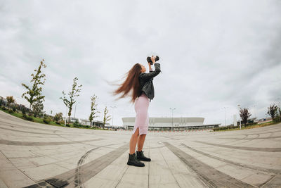 Rear view of woman walking on footpath against sky