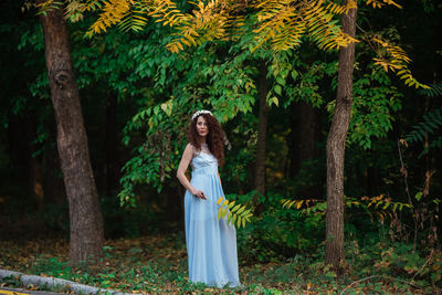 Woman standing by tree in forest