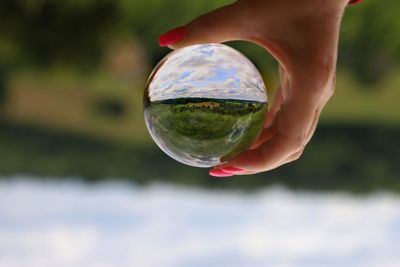 Close-up of hand holding crystal ball outdoors