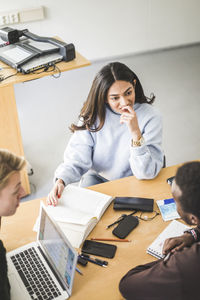 Young woman listening to friends in classroom