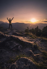 Man standing on mountain against sky during sunset