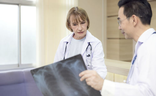 X-ray prints are examined by hospital staff. while looking at an x-ray image, two male medics