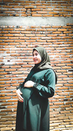 Low section of woman standing against brick wall