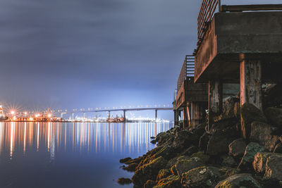 Illuminated bridge over sea against sky