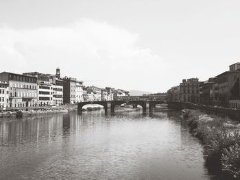 Bridge over river in city against sky