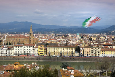 Aerial view of buildings and river in town against sky