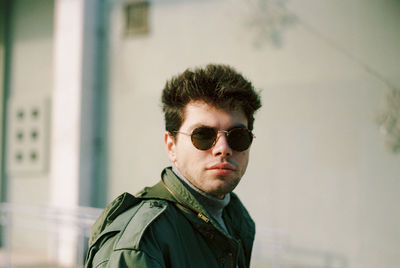 Portrait of young man wearing sunglasses against wall