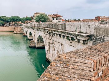 Arch bridge over river against buildings