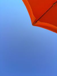 Low angle view of red umbrella against clear blue sky