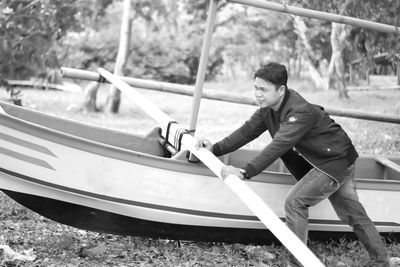 Full length of man holding boat in water