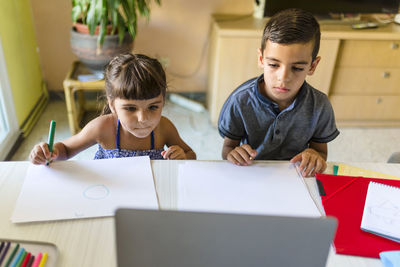 Sister and brother taking online classes at home