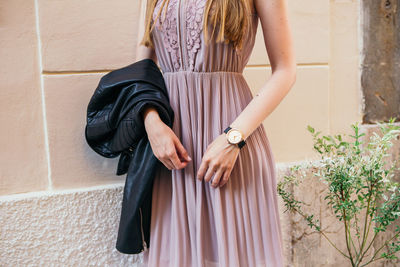 Midsection of woman standing against wall