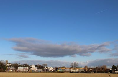 Buildings on field against blue sky