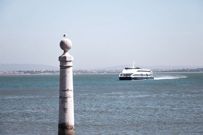 Seagull perching on wooden post in sea against clear sky