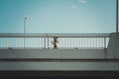 Woman running on bridge in city against sky