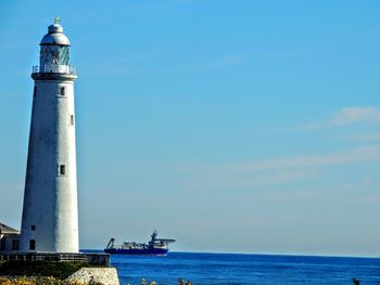 Lighthouse by sea against sky