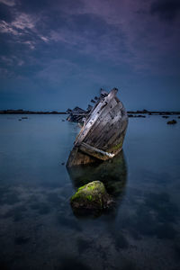 Abandoned boat on sea against sky