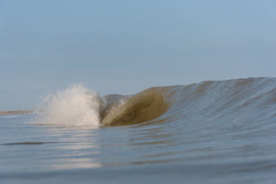 Water splashing in sea against clear sky
