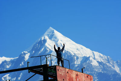 Man standing on snowcapped mountain against blue sky