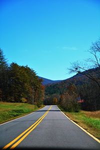 Empty road amidst trees against sky