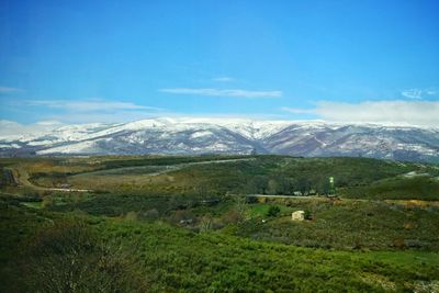 Scenic view of landscape and mountains against blue sky