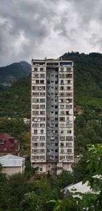 Residential building by mountain against sky