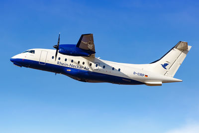 Low angle view of airplane flying against clear blue sky