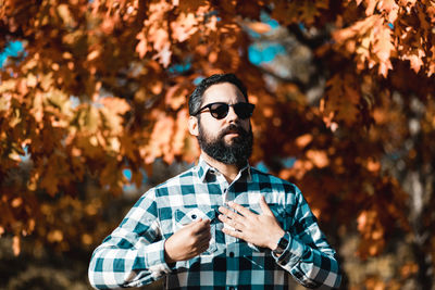 Young man wearing sunglasses standing outdoors during autumn