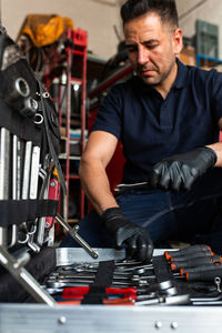 Front view of male technician picking screwdriver bits from tool box while working in garage