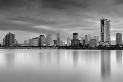 Scenic view of sea by city against cloudy sky