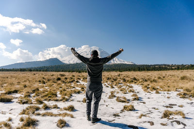 Rear view of man standing on snowcapped mountain against clear blue sky