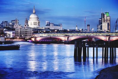 Illuminated millennium bridge over thames river by st paul cathedral at dusk