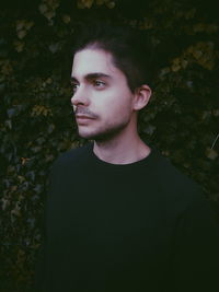 Portrait of young man standing against plants