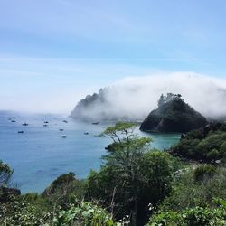 Scenic view of sea by mountain against sky