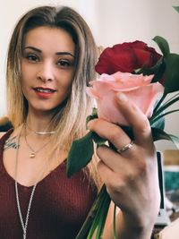 Portrait of a beautiful young woman holding red rose