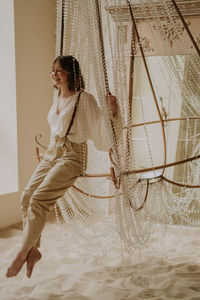 Young female in victorian shirt sitting in giant crystal chandelier and smile